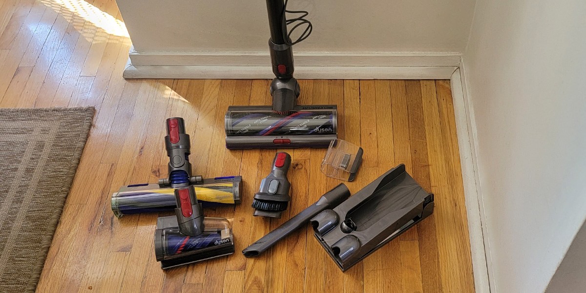 Dyson V15 Detect on hardwood flooring surrounded by accessories Dyson V15 Detect on hardwood flooring surrounded by accessories