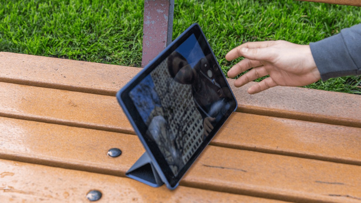 Apple iPad Air on bench with hand reaching toward it Apple iPad Air on bench with hand reaching toward it