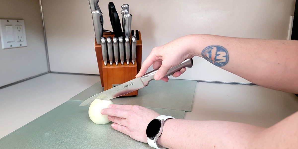 McCook Knife Set on kitchen counter with hand using knife to cut onion in front McCook Knife Set on kitchen counter with hand using knife to cut onion in front