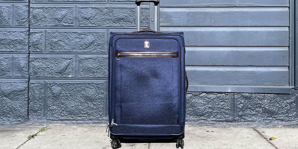 Travelpro Platinum Elite Softside Expandable Checked Luggage on sidewalk in front of wall Travelpro Platinum Elite Softside Expandable Checked Luggage on sidewalk in front of wall