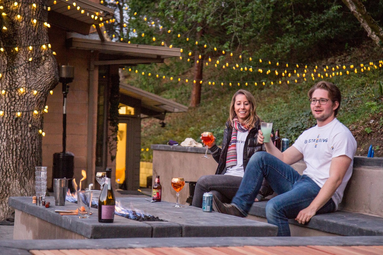 a man and a woman drinking alcohol outdoors with string lights lighting the night