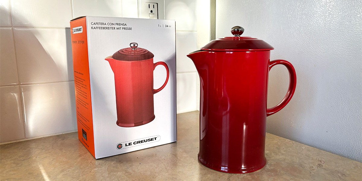 Red Le Creuset French Press on countertop next to product packaging Red Le Creuset French Press on countertop next to product packaging