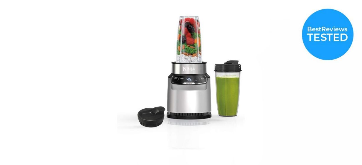 Ninja BN401 Nutri Pro Compact Personal Blender with fruit inside it, next to a smoothie cup