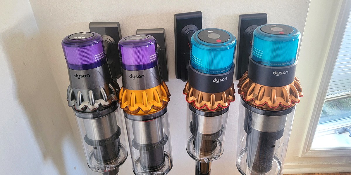 Several Dyson vacuums leaning against wall
