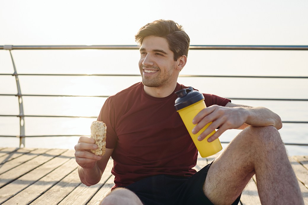 Man drinking water with protein bar