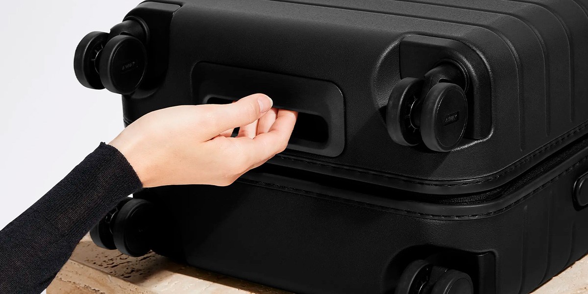 Away Carry-On on side with hand on handle